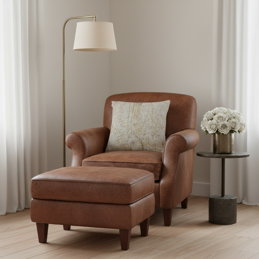 A brown leather armchair with a matching ottoman in a styled living room setting, featuring a patterned throw pillow, a floor lamp, and a side table with white flowers.