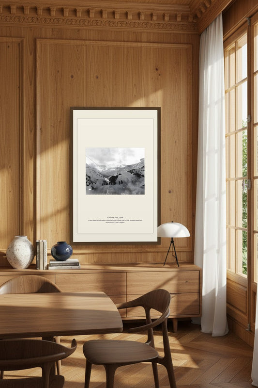 Framed Chilkoot Pass photo in a wood-paneled dining room above a sideboard with ceramic vases