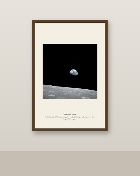 Framed Earthrise print in a dark wood frame on a soft neutral wall