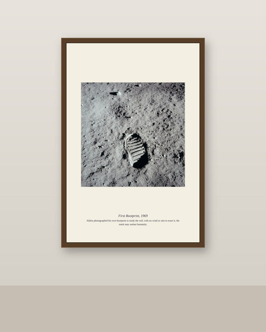 First Bootprint photo in a slim brown frame on a neutral wall above a light baseboard