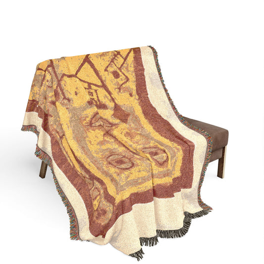 God of War woven throw blanket draped over a wooden bench, rust and golden-yellow abstract woven design