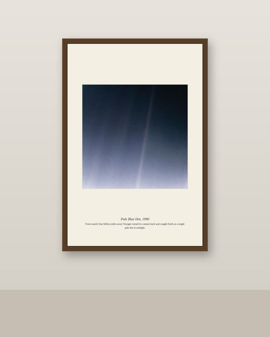Pale Blue Dot print in a dark wood frame on a plain wall