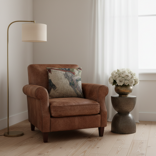A brown leather armchair with a patterned throw pillow in a bright room, next to a floor lamp and a small side table with white flowers.