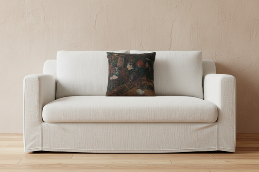 A cream-colored slipcovered loveseat sofa with a dark, patterned decorative throw pillow, set against a textured beige wall and light wood flooring.