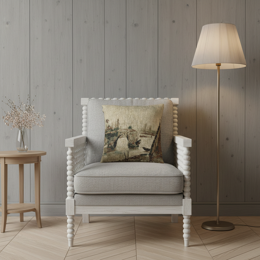 A light gray upholstered armchair with a white beaded frame, styled in a room setting with a decorative throw pillow, a wooden side table with a vase, and a floor lamp against a gray wood-paneled wall.