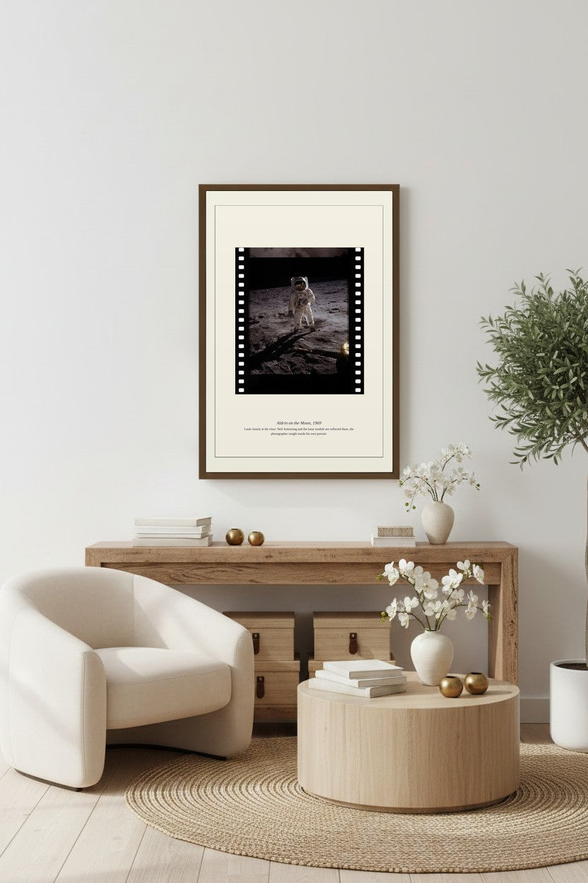 Aldrin on the Moon print framed above a light wood console beside a cream armchair