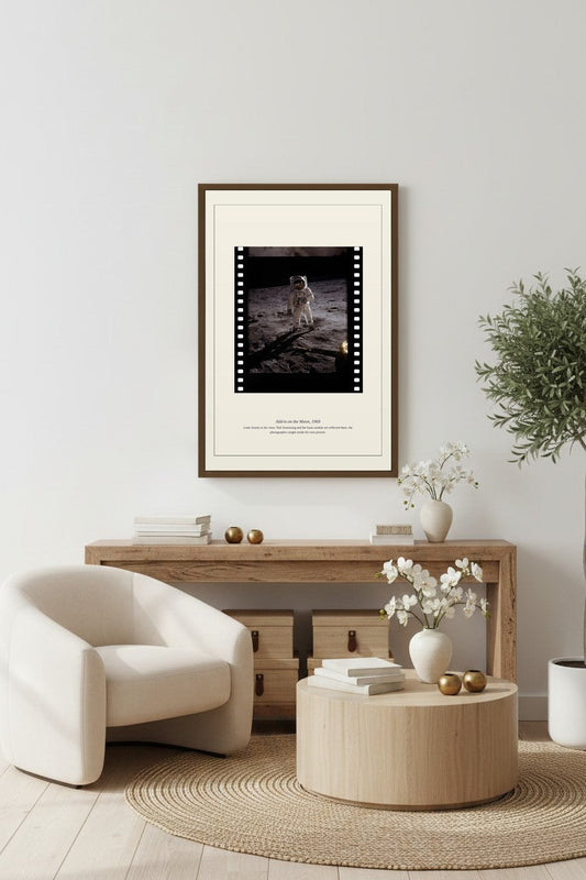 Aldrin on the Moon print framed above a light wood console beside a cream armchair