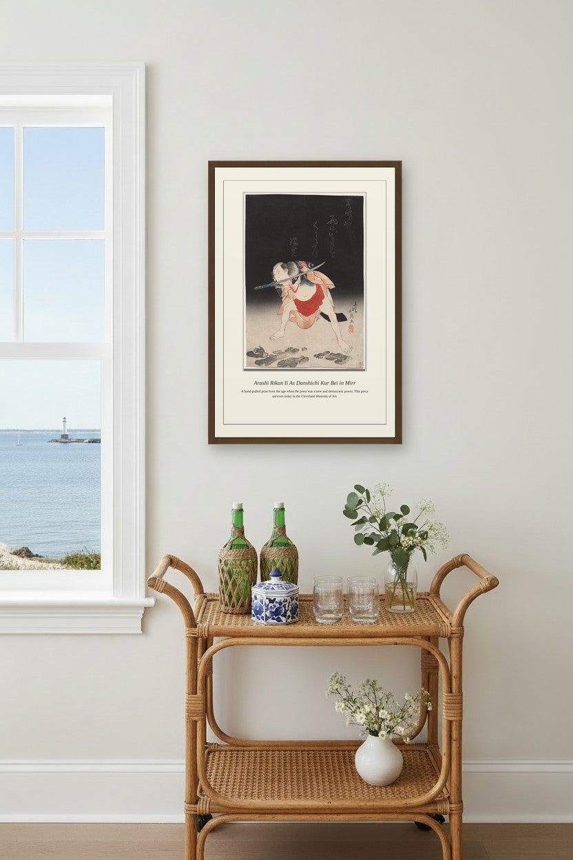 Framed kabuki print above a rattan bar cart near a window overlooking the sea
