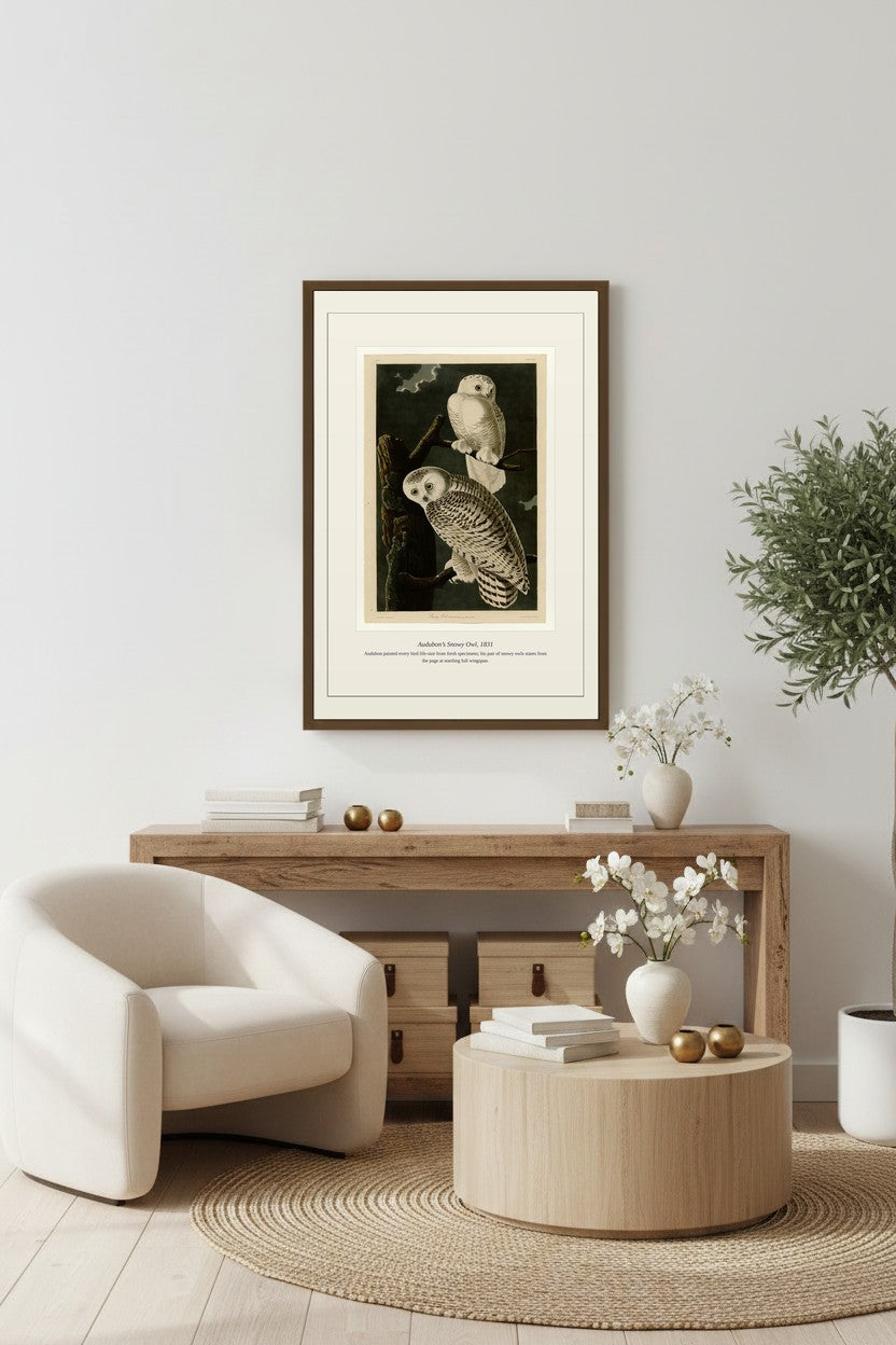 Snowy Owl print above a light wood console table beside a white armchair