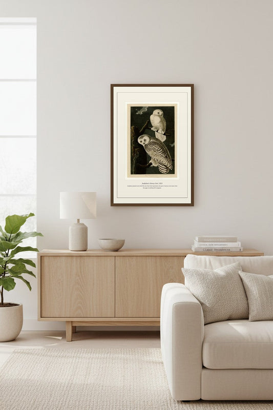 Snowy Owl print above a light wood sideboard beside a potted plant
