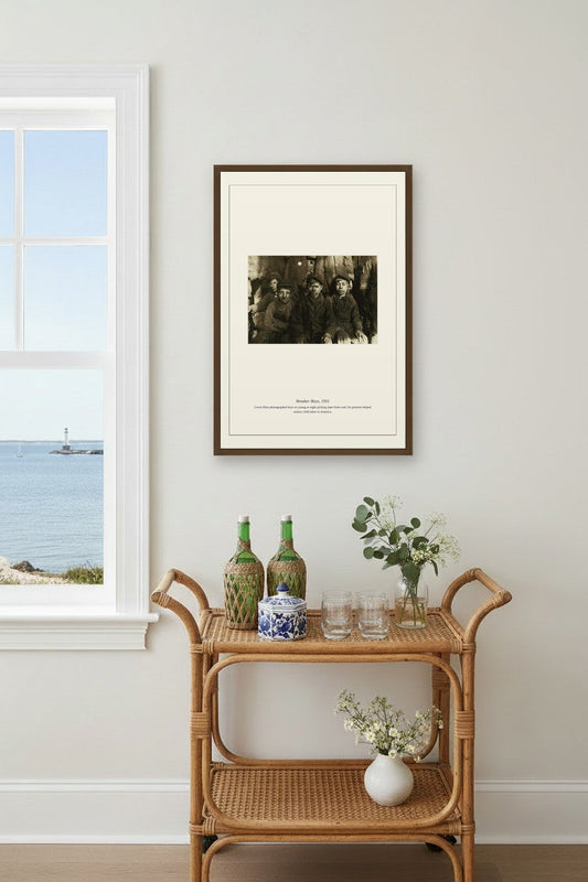 Breaker Boys photograph framed above a rattan bar cart near a window overlooking the sea