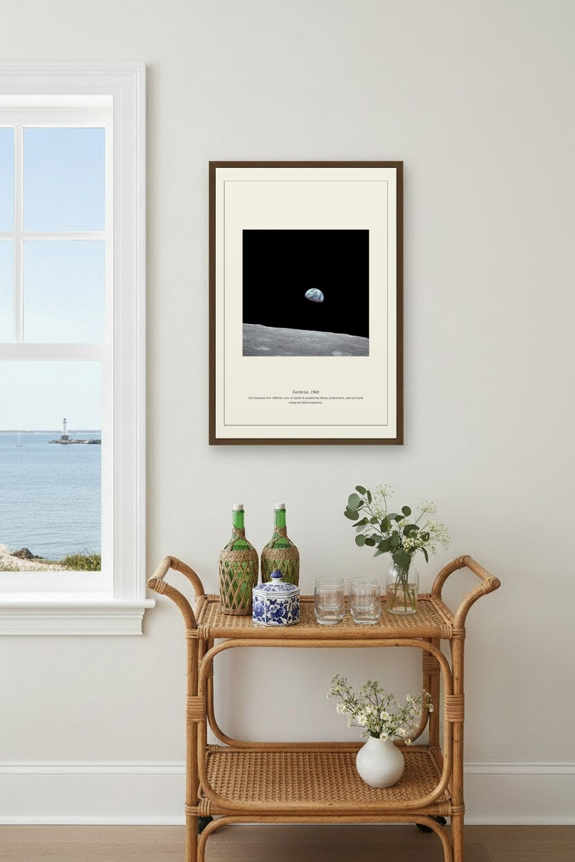 Earthrise print above a rattan bar cart beside a window with a lighthouse view