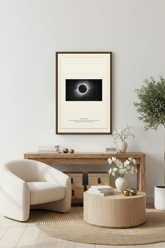 1919 Eclipse print framed above a light wood console table with an armchair nearby