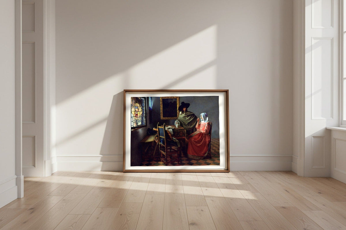 The Glass of Wine — Johannes Vermeer Fine Art Poster shown framed and leaning against a wall in a sunlit room