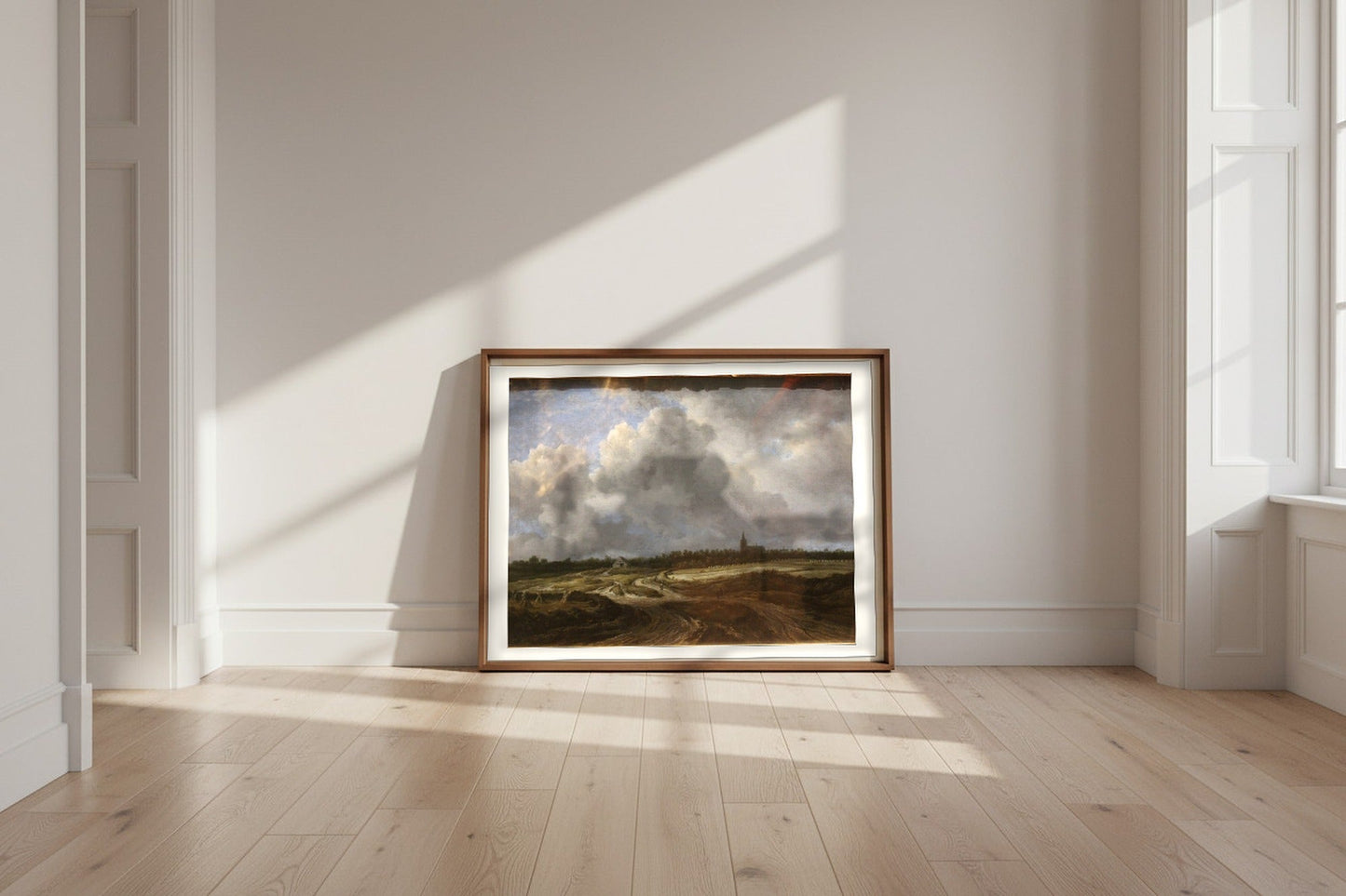 A Wooded Village behind Dunes — Jacob van Ruisdael Fine Art Poster shown framed and leaning against a wall in a sunlit room