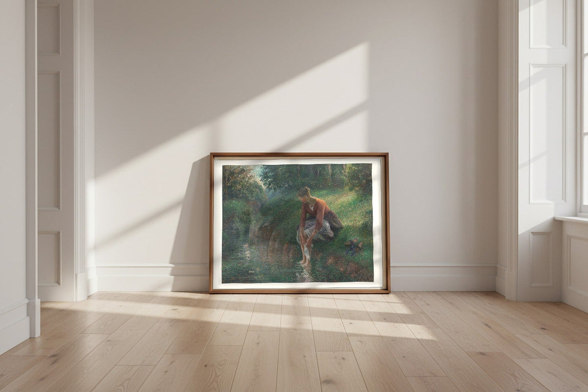 Woman Bathing Her Feet in a Brook — Camille Pissarro Fine Art Poster shown framed and leaning against a wall in a sunlit room