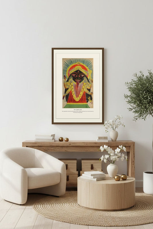 Framed Goddess Kali print above a wood console table with a bouclé chair and olive tree