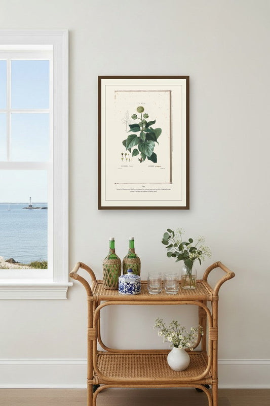 Ivy print framed above a rattan bar cart beside a window with an ocean view