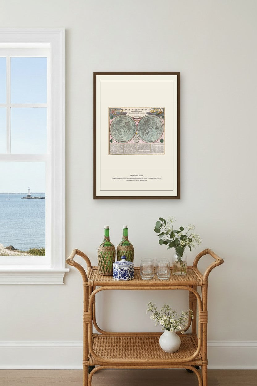 Map of the Moon chart framed above a rattan bar cart near a window with an ocean view