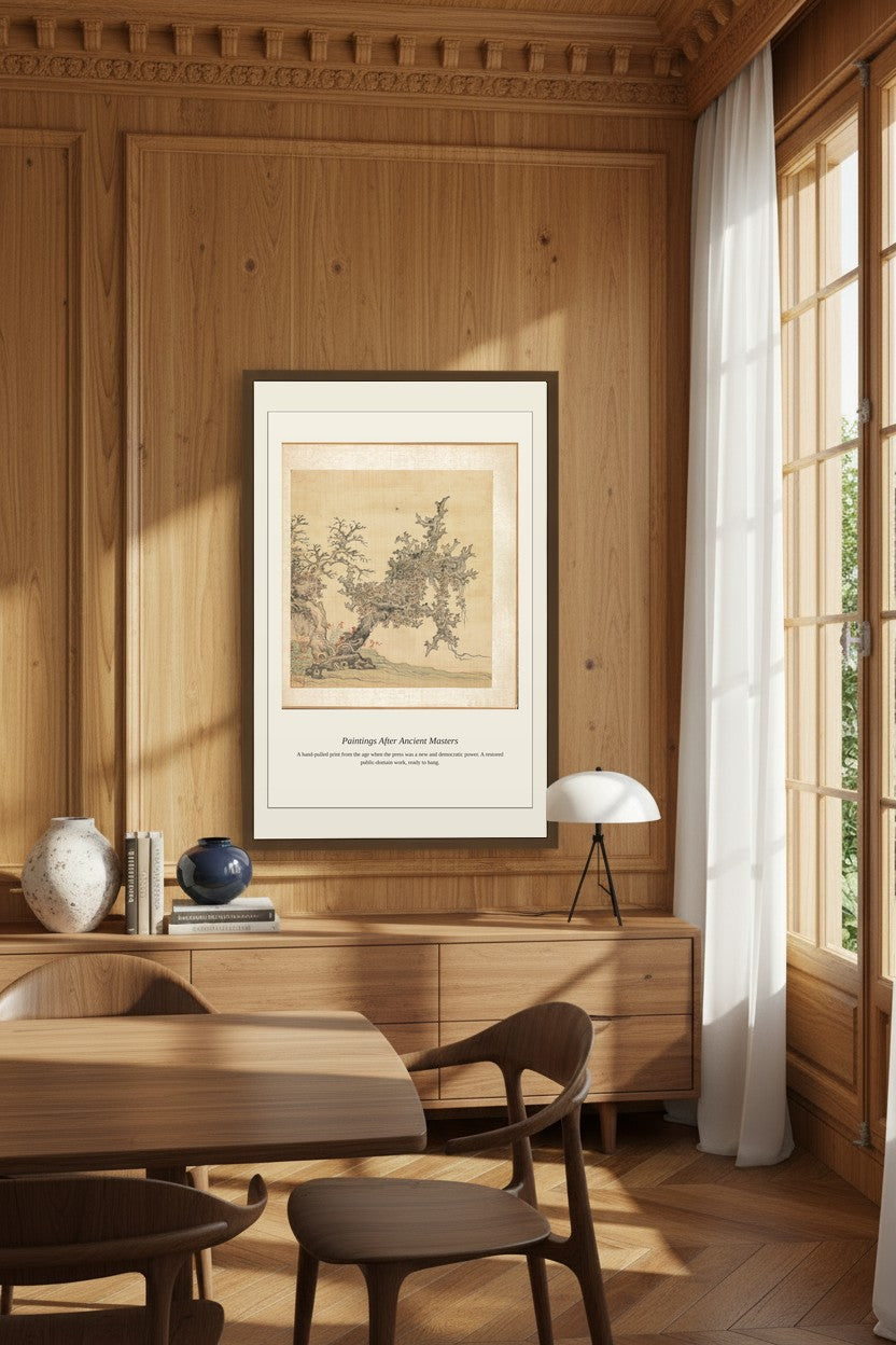 A framed art print featuring a vintage botanical illustration hangs on a wood-paneled wall in a warm, modern dining room with wooden furniture and a window with sheer curtains.