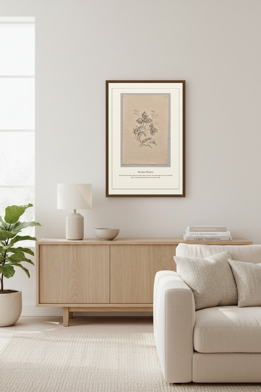 A framed botanical art print with a beige background and black illustration, styled in a minimalist living room above a light wood sideboard.