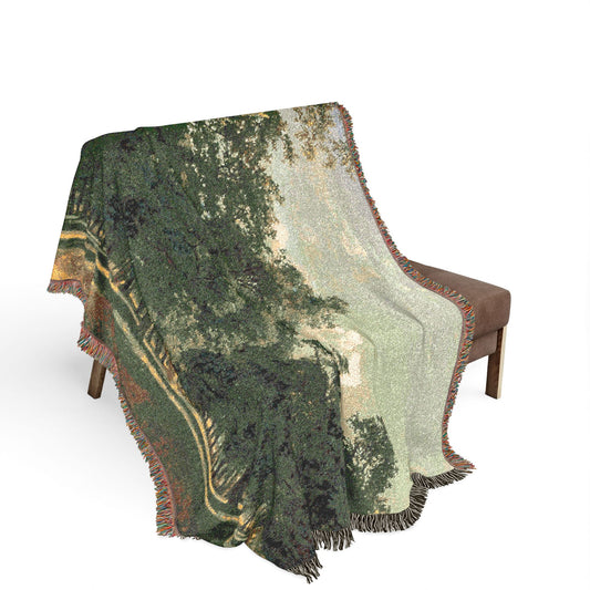 Prater Landscape blanket draped over wooden bench, green tree canopy landscape, golden earth tones, fringe edge