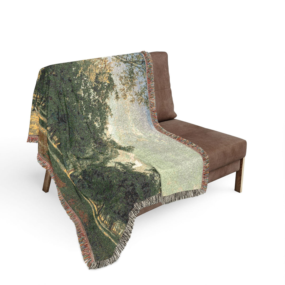 Prater Landscape blanket draped on gray sofa, lush green tree landscape with pale sky, soft earth tones, fringe edge