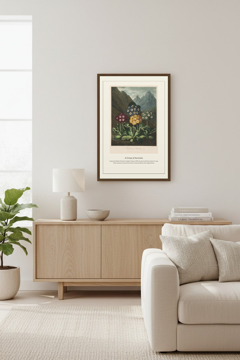 A framed black and white portrait print of Mother Teresa hangs on a light beige wall in a modern, minimalist living room with a light wood sideboard, a white sofa, and a potted plant.