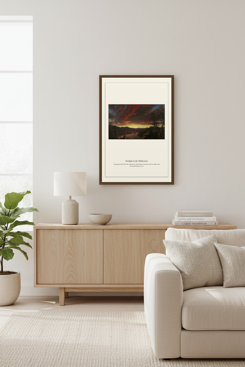 Twilight in the Wilderness landscape print framed above a low wood console table beside a potted plant