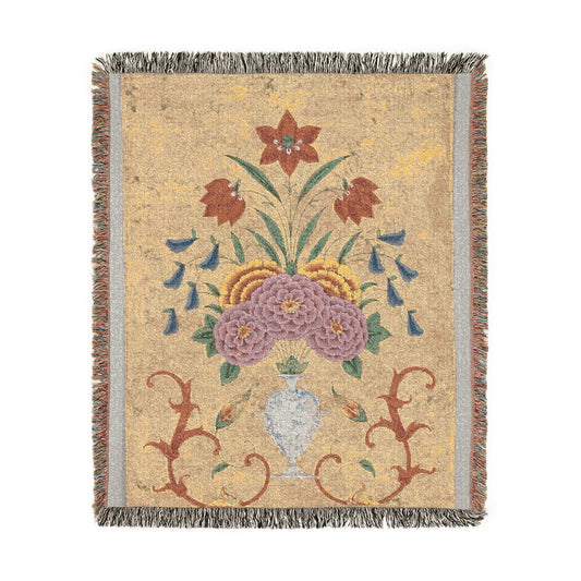 Vase with flower arrangement woven throw blanket flat lay, sandy gold ground with purple blooms and red scrollwork