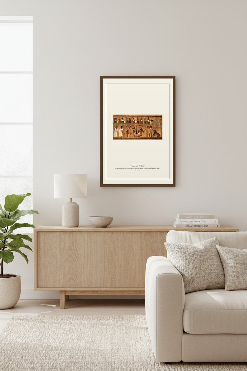 Weighing of the Heart artwork framed above a light wood sideboard with a table lamp and bowl