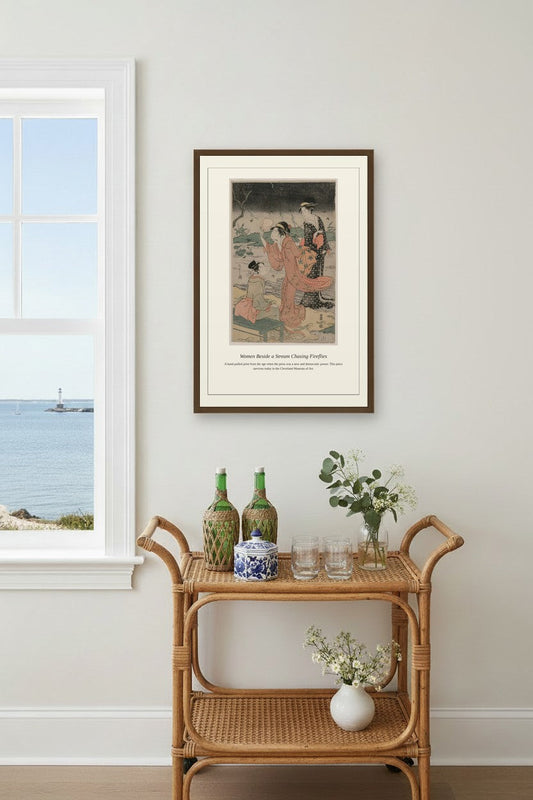 Women Beside a Stream Chasing Fireflies framed above a light wood sideboard beside a curtained window